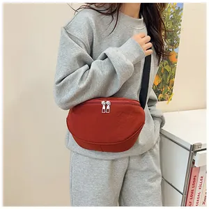 Detail of brick red canvas crossbody bag with double zippers and black wide shoulder strap