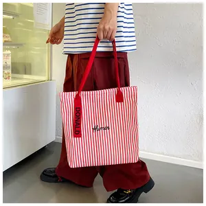 Detail of red and white striped canvas tote bag featuring Humin embroidery and soft straps