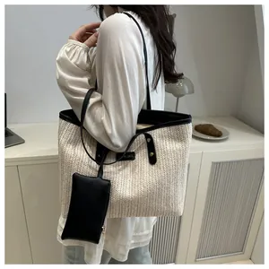 Detail of woven straw tote bag with black leather trim and small detachable purse