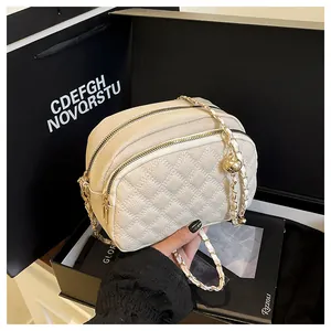 Dettaglio della borsa a tracolla trapuntata crema con cerniere e catena dorate