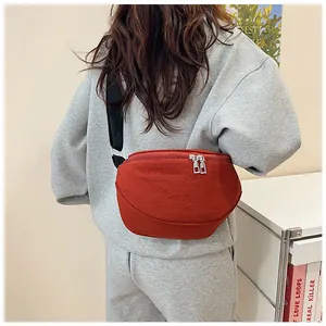 Detail of red nylon saddle crossbody bag featuring silver double zippers and black strap
