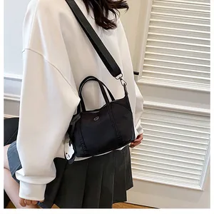 Close-up of black nylon tote bag featuring a cute white cat pendant and wide strap