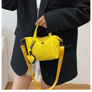 Close-up of bright yellow nylon tote bag featuring a cute panda charm and metal emblem