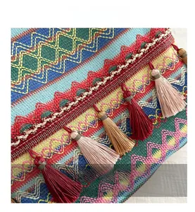 Macro shot of ethnic bohemian embroidery details and colorful tassels on woven fabric