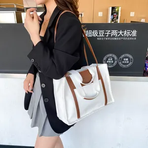 Stylish canvas tote bag with brown leather trim shown in a modern lifestyle cafe setting
