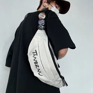 Cream canvas crossbody chest bag with TANBRNU print and decorative badges for street style