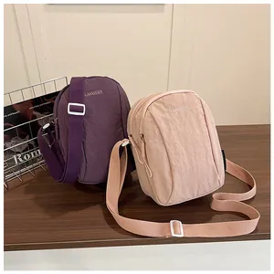 Detail of waterproof nylon crossbody bags with embroidered logo and wide straps