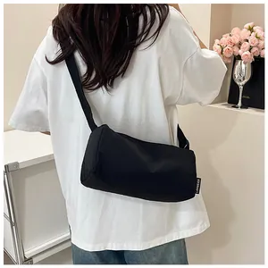Close-up of black nylon cylinder crossbody bag with adjustable strap and side brand label