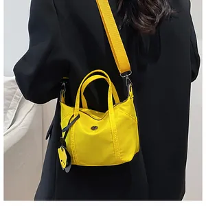 Side view of a bright yellow nylon mini tote bag worn with a chic black blazer outfit
