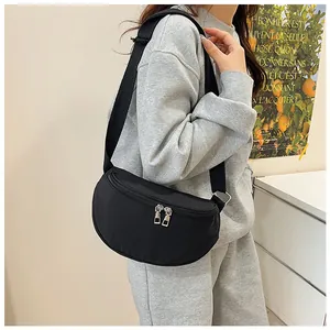 Detail of black crescent crossbody bag showing double metal zippers and nylon texture