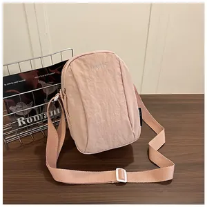 Detail of light pink waterproof nylon crossbody bag with adjustable strap and brand logo