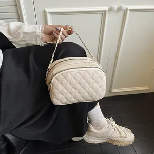 Borsa a tracolla trapuntata beige con catena dorata e doppia zip mostrata dalla modella