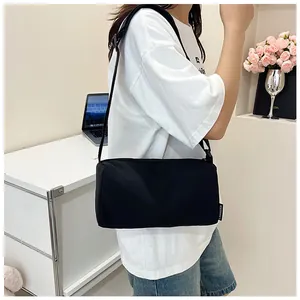 Side view of black nylon crossbody pillow bag with brand tag shown on a female model