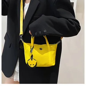 Close-up of bright yellow nylon mini tote bag with panda charm on black blazer