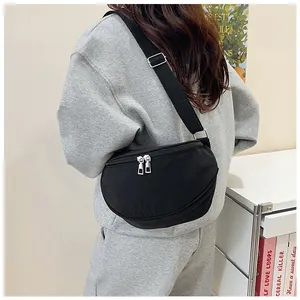Close-up of black nylon crescent bag with adjustable strap and dual silver zippers