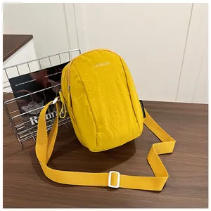 Close-up of bright yellow nylon crossbody bag with adjustable strap and dual zippers