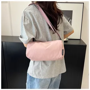 Model wearing a light pink nylon pillow bag showing adjustable strap and side brand label