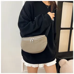 Detail of khaki crescent crossbody bag with silver double zippers and wide black strap