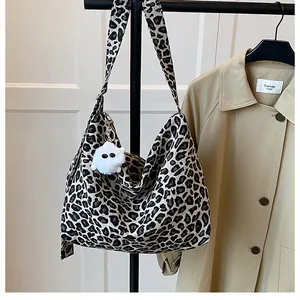 Gros plan d'un sac cabas en toile léopard avec un porte-clé en peluche blanc doux