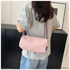 Detail of pink nylon barrel crossbody bag featuring logo label and wide shoulder strap