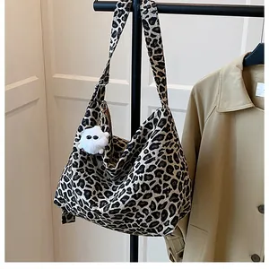Détail du sac cabas léopard en toile avec texture nette et breloque peluche blanche