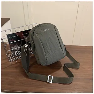 Detail of grey-green nylon crossbody bag with logo print and adjustable strap