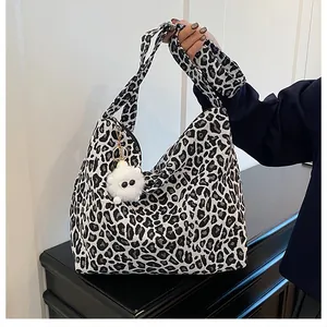 Détail du sac fourre-tout léopard avec bandoulière large et pendentif en peluche doux
