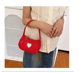 Detailansicht der roten Mini-Handtasche mit weißem Herz-Patch und goldenem Bogen
