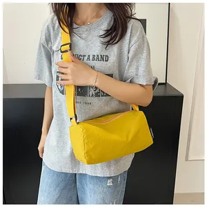 Macro detail of vibrant yellow nylon cylinder bag with adjustable shoulder strap and logo