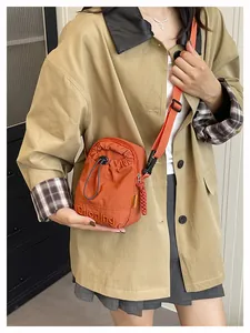 Vue détaillée d'un mini sac bandoulière en nylon orange porté par un mannequin femme