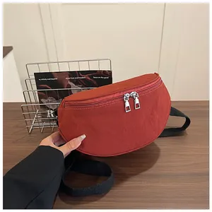 Close-up of red nylon crescent bag with silver dual zippers and black adjustable strap