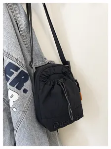 Détail de la petite sacoche noire en nylon avec cordon de serrage et étiquette orange