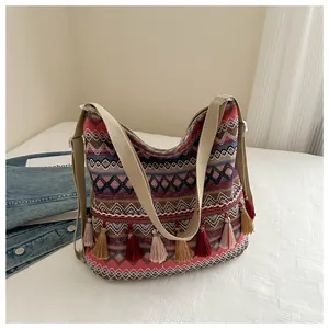 Detailed shot of pink ethnic shoulder bag with colorful tassels and geometric patterns