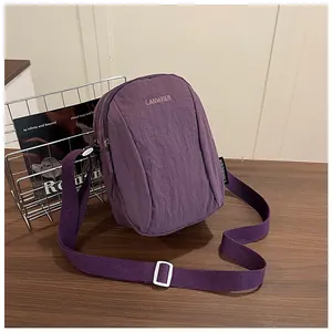 Detail of purple nylon crossbody bag with dual zippers and woven shoulder strap