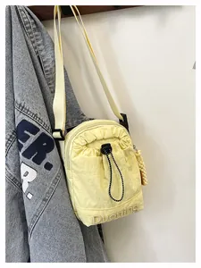 Détail du sac bandoulière en nylon jaune avec cordon et broderie de marque chic