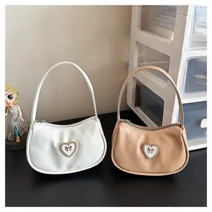 Detail von Handtaschen aus weißem und beige PU-Leder mit funkelnder Herz- und Schleifenschnalle