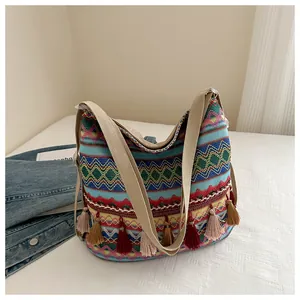 Macro view of bohemian woven tote bag showing colorful textures and tassel details