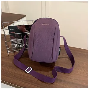 Close-up of purple nylon crossbody bag with LANWEIER embroidery on wood surface