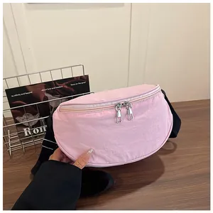 Detailed close-up of pink nylon crescent bag featuring smooth double zippers and black strap