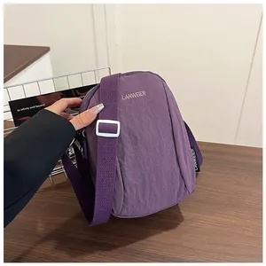 Detail of purple nylon crossbody bag featuring textured fabric and adjustable strap