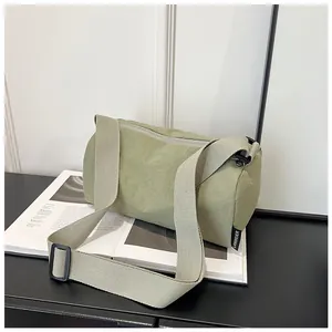 Detail of light green nylon cylinder bag with adjustable strap and brand woven label