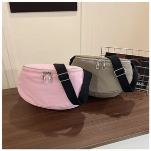 Detail of pink and khaki crescent crossbody bags with adjustable straps on wooden desk