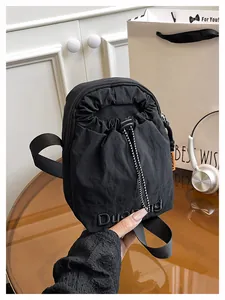 Détail du sac bandoulière en nylon noir avec fermeture à cordon et poche zippée latérale
