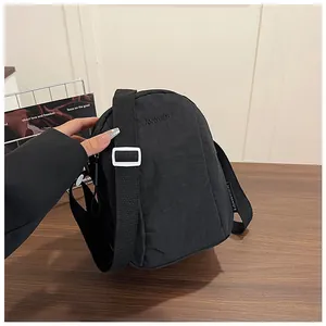 Detail showing high-quality waterproof black nylon fabric and brand embroidery on the bag
