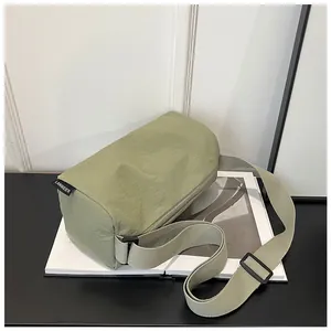 Detail of sage green nylon crossbody bag showing strap buckle and side brand label