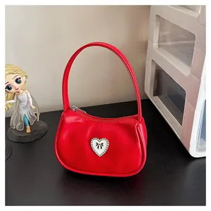 Detail einer roten Mini-Handtasche aus Leder mit Strass-Herz und Schleifen-Applikation