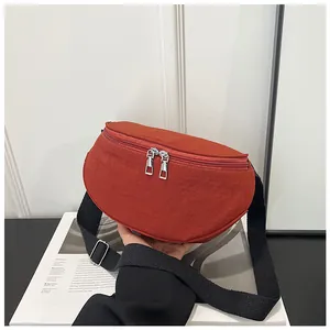 Detail of orange nylon saddle bag featuring dual metal zippers and a wide black strap