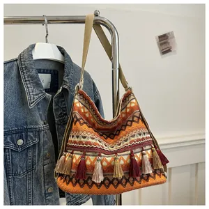 Close-up of bohemian woven shoulder bag with orange geometric patterns and colorful tassels