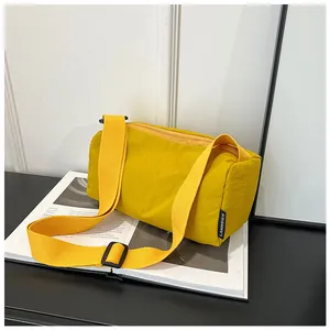 Detail of yellow nylon sports duffel bag with black brand label and wide shoulder strap