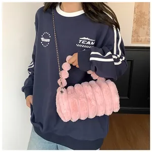 Détail du sac oreiller en peluche rose avec pompons doux et bandoulière chaîne argent